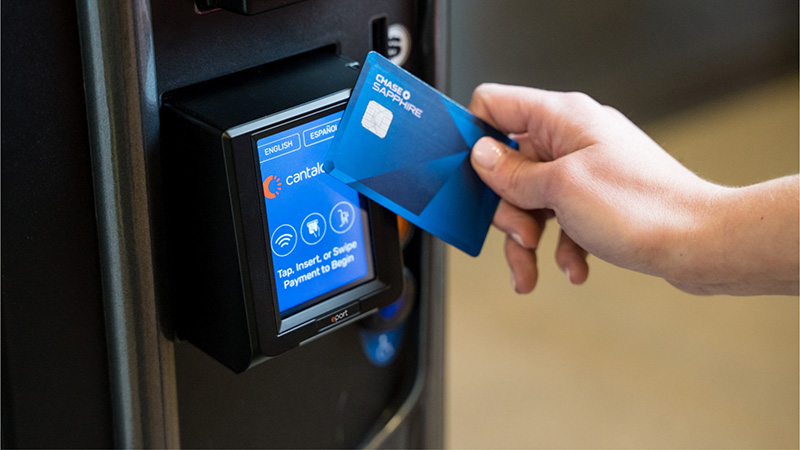 Vending machine cashless payment UK showing a customer tapping a contactless card on a modern vending machine card reader to purchase a drink